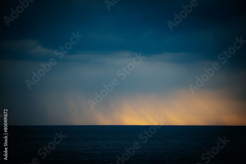 Dark ominous sea with sunset on the horizon in spring. Soft selective focus. Artificially created grain for the picture