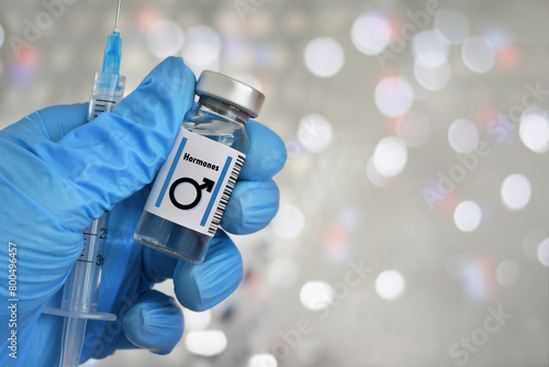 Foto Blue gloved hand holding a vial with male symbol, hormones injections, concept s