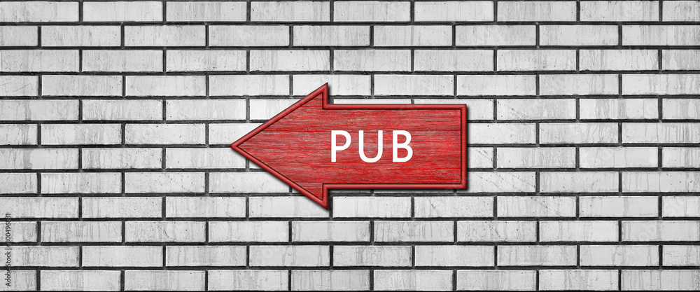 Red wooden arrow sign with the inscription PUB hanging on a white brick wall. Left arrow pointer Red wooden arrow sign with the inscription PUB hanging on a white brick wall. Left arrow pointer