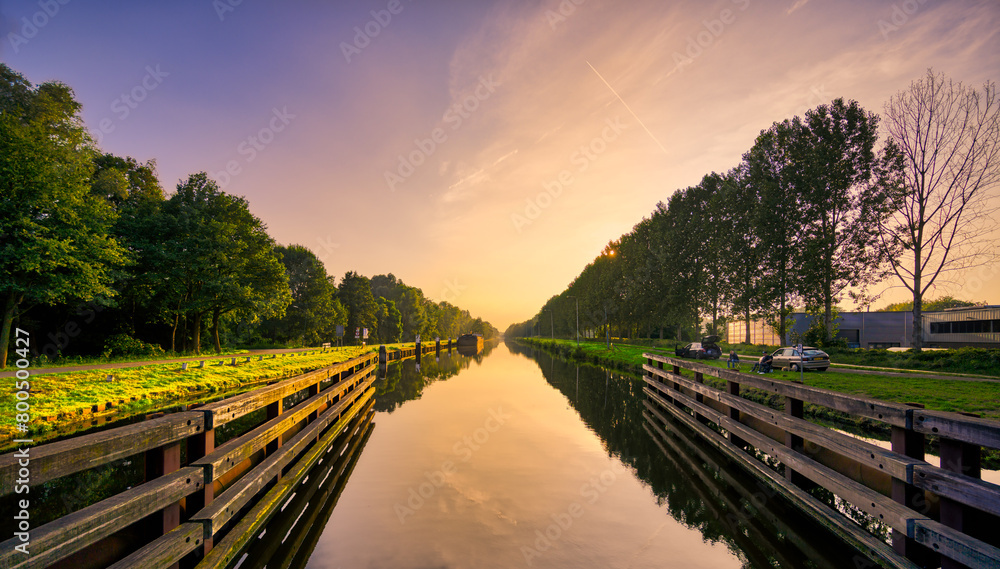 Sunset over the still waters of the Wilhelminakanaal canal in Noord-Brabant, The Netherlands. Sunset over the still waters of the Wilhelminakanaal canal in Noord-Brabant, The Netherlands.