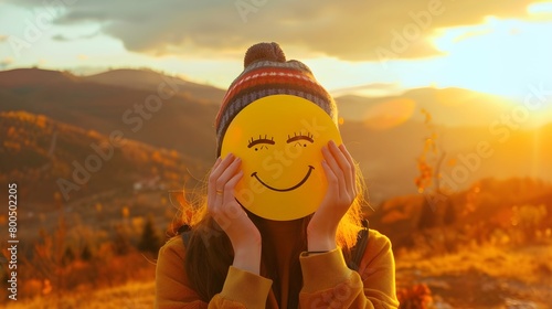 Close up of young woman holding happy smile face on background epic sunset in mountains at autumn sunny day, good feedback rating and positive customer review, satisfaction survey, mental health photo