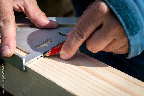 Drawing an angle mark on the wood with a pencil, carpentry works © STOATPHOTO