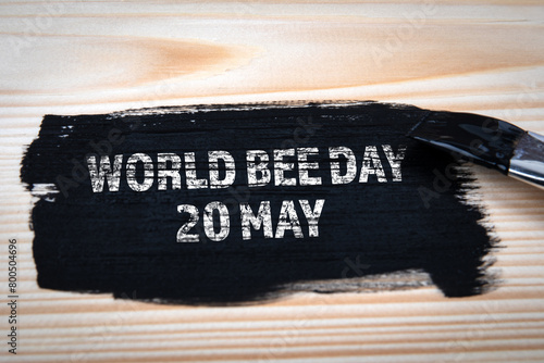 World Bee Day 20 May. Black paint and paint brush on wood texture background