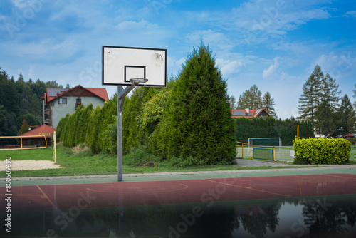 Boisko do gry w koszykówkę na świeżym powietrzu w otoczeniu zieleni z ciekawym odbiciem u spodu photo