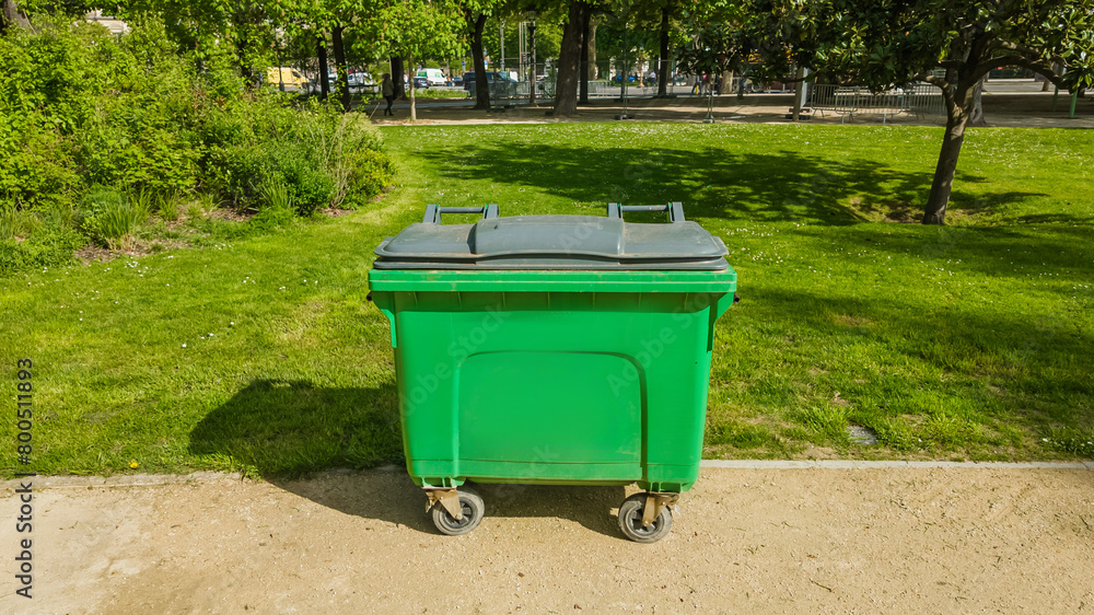 Green waste container in a sunny park setting, depicting recycling and environmental conservation with urban park management related to Earth Day and World Environment Day Green waste container in a sunny park setting, depicting recycling and environmental conservation with urban park management related to Earth Day and World Environment Day