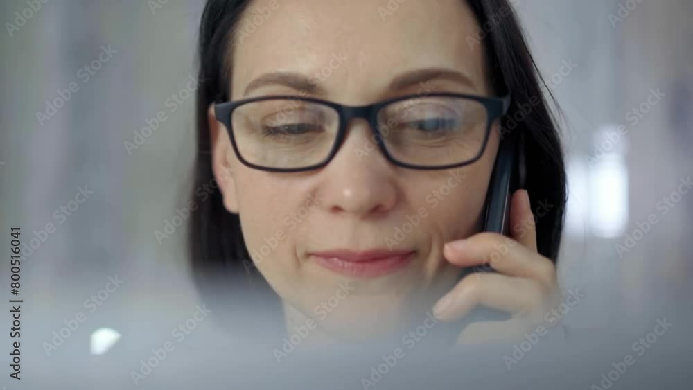 Cheerful smiling woman with glasses using a mobile phone, blurred background. Lifestyle and business concepts Cheerful smiling woman with glasses using a mobile phone, blurred background. Lifestyle and business concepts