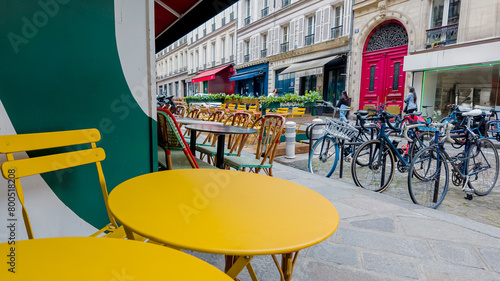Paris  France  April 14th  2024 Colorful sidewalk cafe setting with yellow tables and chairs on a European city street  suggesting urban lifestyle and al fresco dining concepts