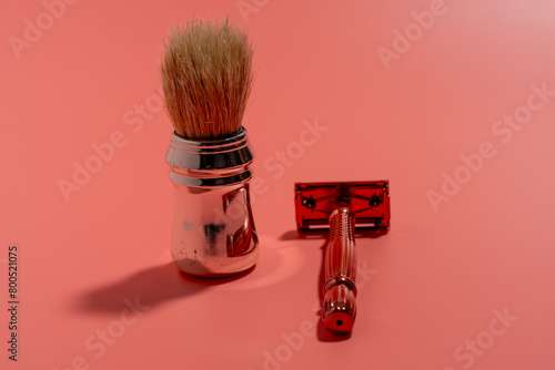 Metal razor and pen brush on a pink background. Razor close-up.