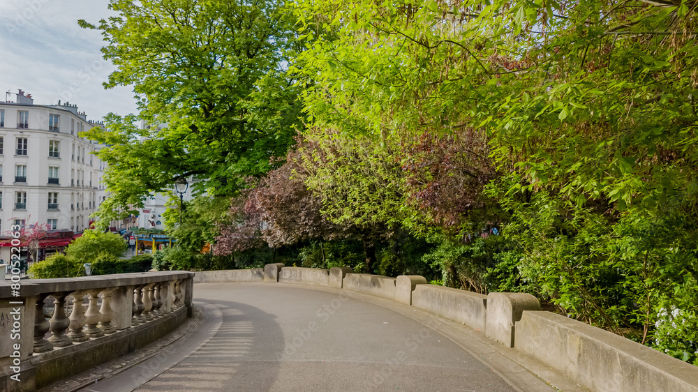 Sunny springtime view of a serene Parisian park pathway flanked by lush greenery, ideal for Earth Day and International Day of Forests themes Sunny springtime view of a serene Parisian park pathway flanked by lush greenery, ideal for Earth Day and International Day of Forests themes
