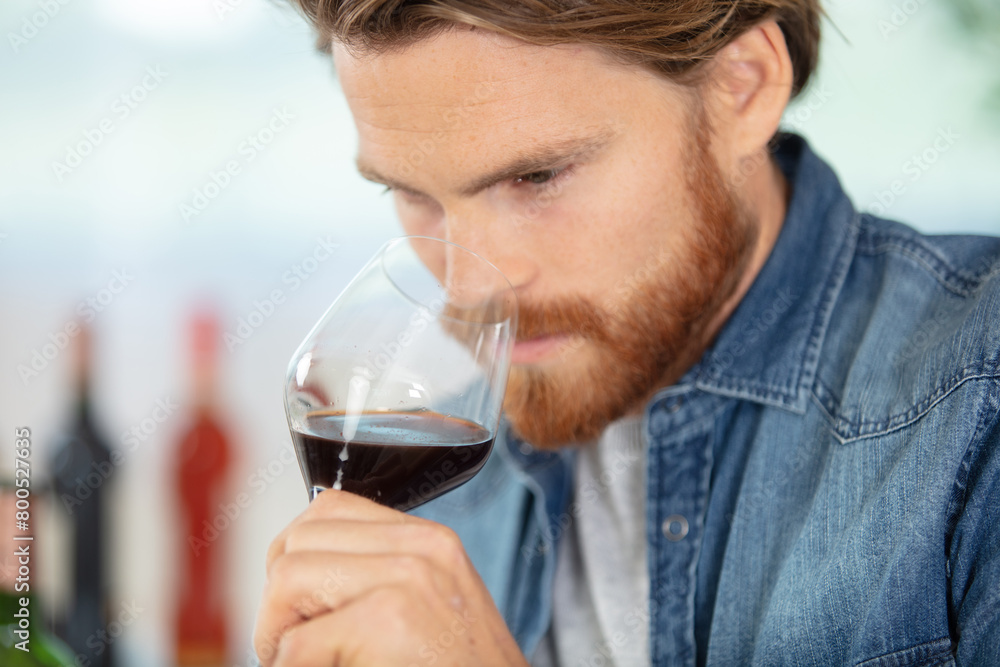 adult caucasian man smelling glass of red wine