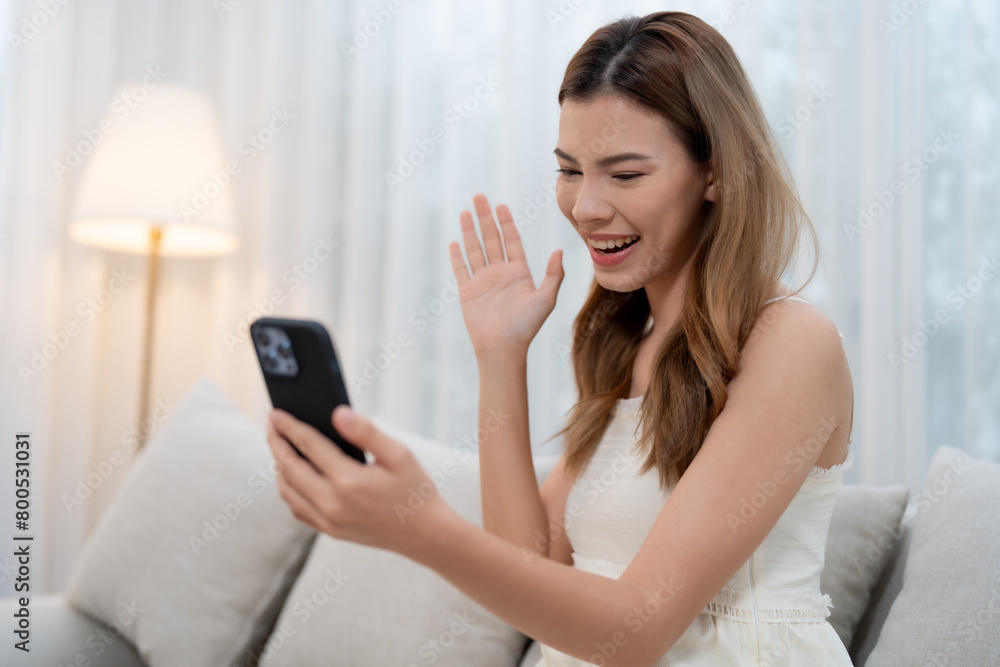 A young woman uses a smartphone to greet family or friends via video call. During the long holiday at her house there is a modern communication concept. A young woman uses a smartphone to greet family or friends via video call. During the long holiday at her house there is a modern communication concept.