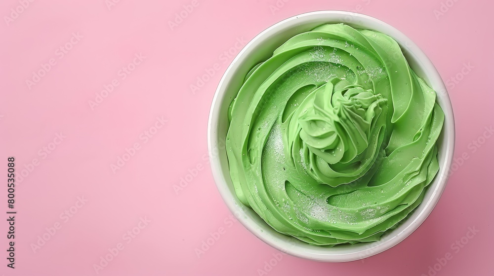 A white bowl holds green frosting, atop a pink surface In its center, a green swirl twists A white bowl holds green frosting, atop a pink surface In its center, a green swirl twists