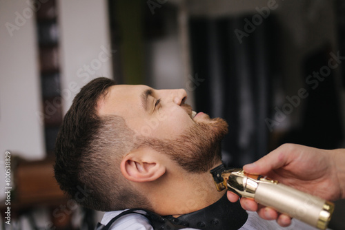 Professional hairdresser uses a hair clipper for fringing hair for a handsome barber man. Barbershop