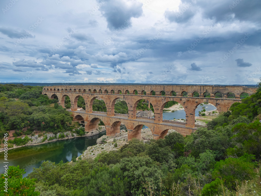 Panoramic view of ancient old Roman Aqueduct Pont du Gard ear Vers-Pon-du-Gard, Occitanie, France, Europe. Landmark over the River Gardon. Unesco world heritage site near Nimes, Languedoc-Roussillon
