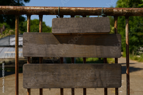 Blank Wooden Signboard Hanging on a Rusty Metal Fence