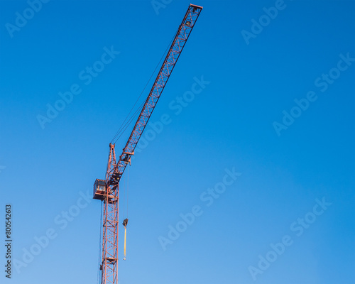 A tower construction crane on the background of a blue sky with clouds. Boom rotary crane with boom. Construction of apartment buildings in the city.