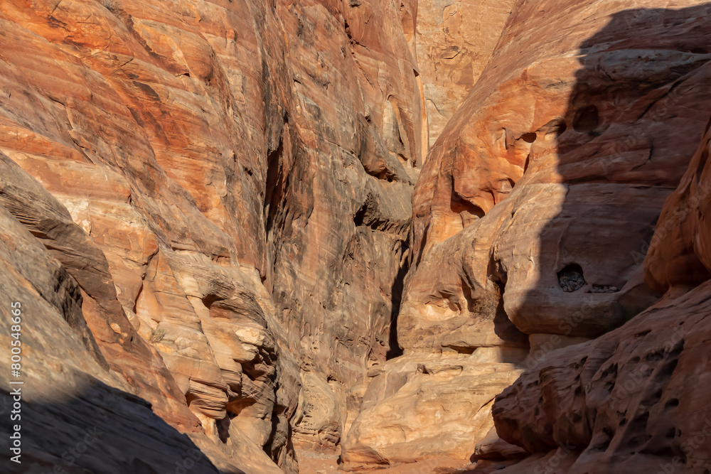 Entrance of the narrow slot canyon along the White Domes Hiking Trail in Valley of Fire State Park in Mojave desert, Nevada, USA. Massive rugged cliffs of striated red and white rock formations