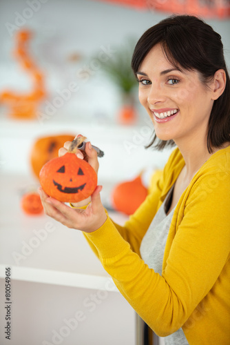 attractive woman drawing on pumpkin