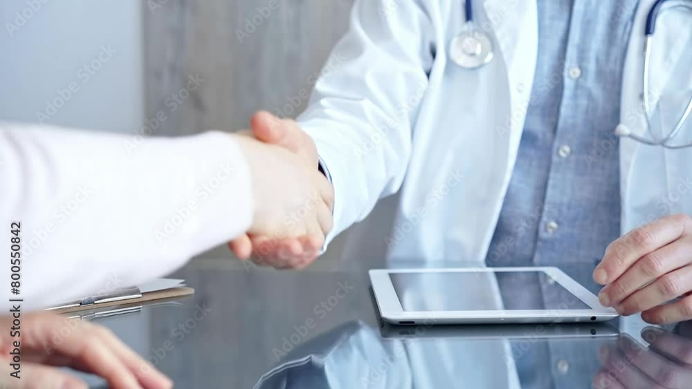 Doctor and patient handshake in clinic setting above the glass table. Medicine concept trust and agreement Doctor and patient handshake in clinic setting above the glass table. Medicine concept trust and agreement
