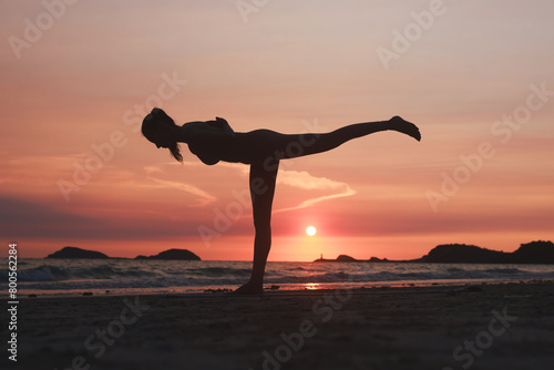 Silhouette workout woman stretching arms and legs exercising during sunset at the beach  Yoga concept