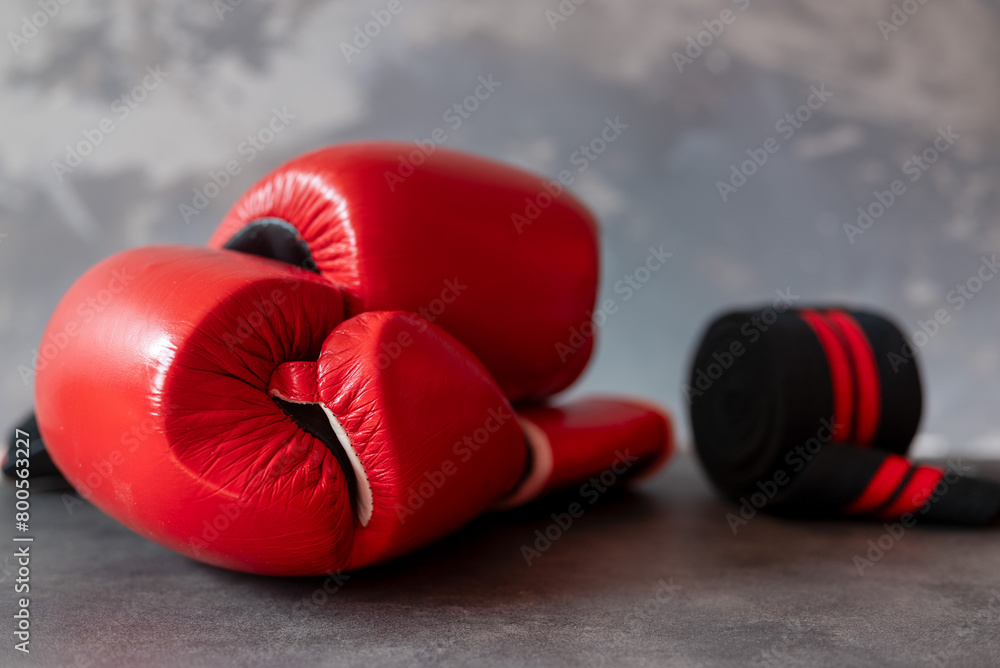 Red boxing gloves and a sports belt with a grey structural background. 