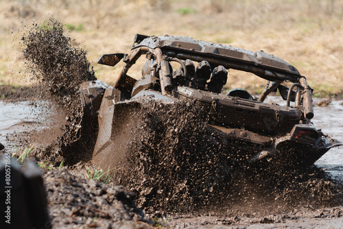An SUV leaves a mud pit at a competition. Buggy in the mud.