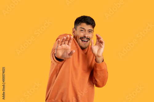 Fotografi Man in Orange Shirt Making Hand Gesture