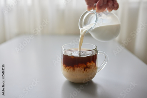 Tableau sur toile Pouring Cream into a Cup of Coffee