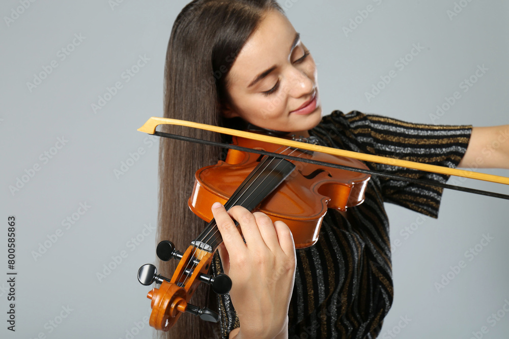 Beautiful woman playing violin on grey background, closeup Beautiful woman playing violin on grey background, closeup