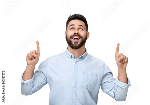 Happy young man with mustache pointing at something on white background