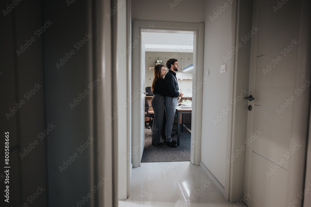 Fototapeta premium In an office, two colleagues share a warm hug, flirting in a positive atmosphere and love.