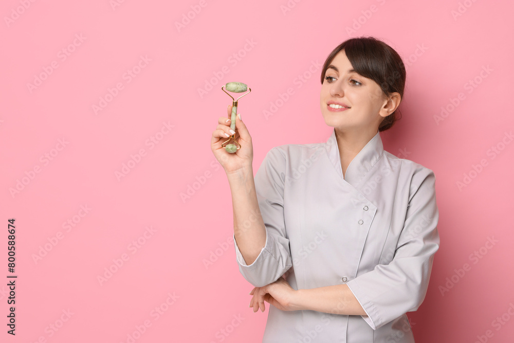 Cosmetologist with facial roller on pink background, space for text Cosmetologist with facial roller on pink background, space for text