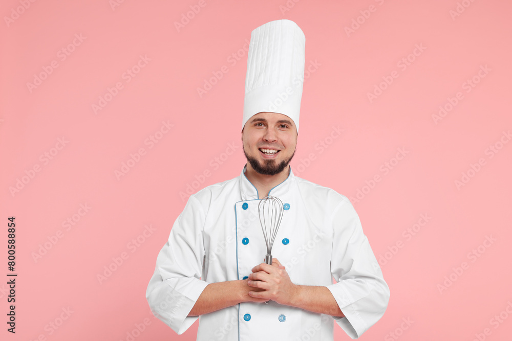 Happy professional confectioner in uniform holding whisk on pink background Happy professional confectioner in uniform holding whisk on pink background