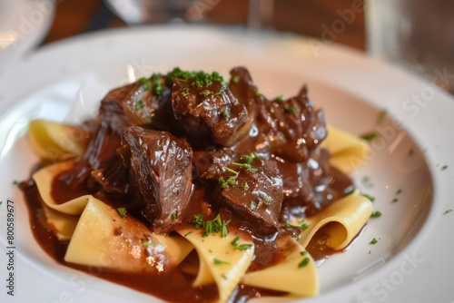 beef cheeks with sauce on a plate of pappardelle pasta in a realistic background © Dekastro