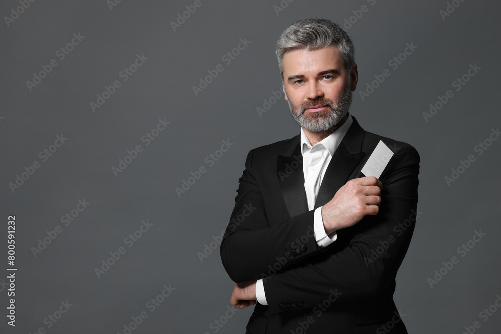 Handsome businessman holding blank business card on grey background. Space for text Handsome businessman holding blank business card on grey background. Space for text