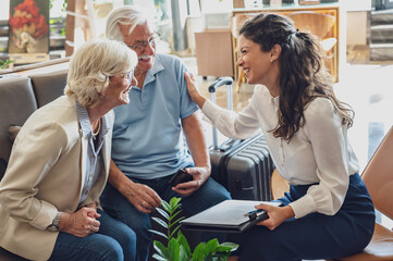 A hotel or travel agency representative is talking with a senior tourist couple offering various tourist services