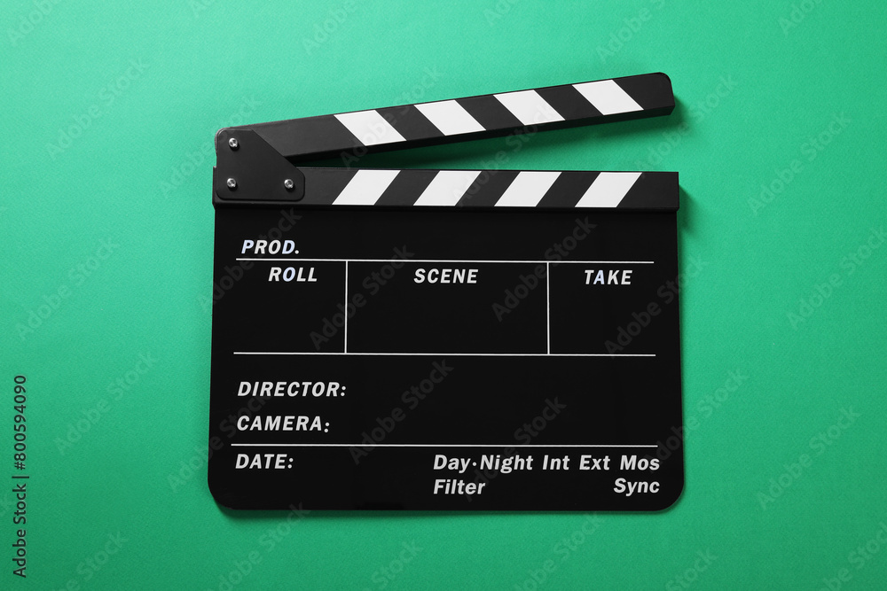 Fototapeta premium One clapperboard on green background, top view