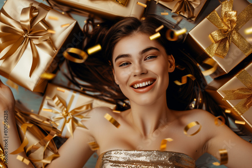 A portrait of a beautiful model surrounded by gifts and confetti in gold tonation photo