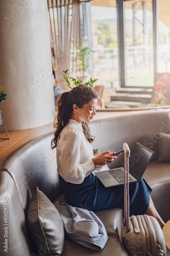 Businesswoman sitting in a hotel lobby, using laptop. Woman working on a business trip using online connections. Business lady went to business trip and stayed at the hotel.