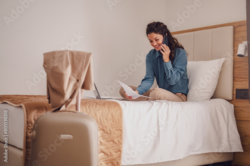 Businesswoman sitting on bed, using laptop. Woman working in hotel room. Business lady went to business trip and stayed at the hotel.