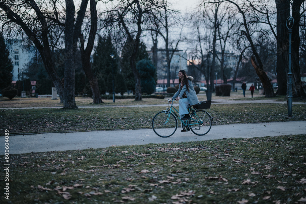 A person enjoys a tranquil bike ride along a path in a quiet, tree-filled park during the early evening hours. A person enjoys a tranquil bike ride along a path in a quiet, tree-filled park during the early evening hours.