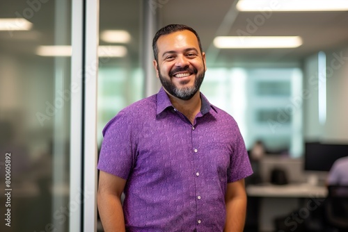 A man in a purple shirt is smiling and posing for a picture