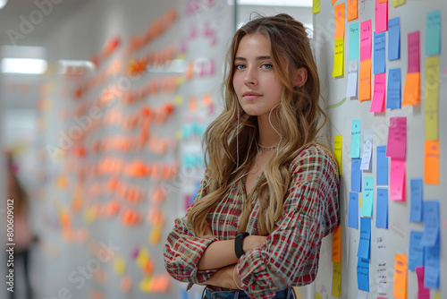 woman standing in an office space - a whiteboard with a lot of post-its in the background