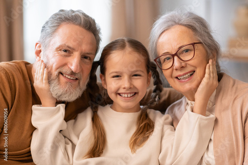 Smiling Grandparents With Their Young Granddaughter Enjoying Family Time Together
