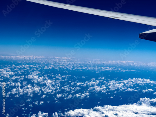 Wing of an airplane seen from the window flying over the Atlantic Ocean  on a vacation trip to the Caribbean  more specifically to Cancun  Mexico  on a direct flight from Madrid  Spain .