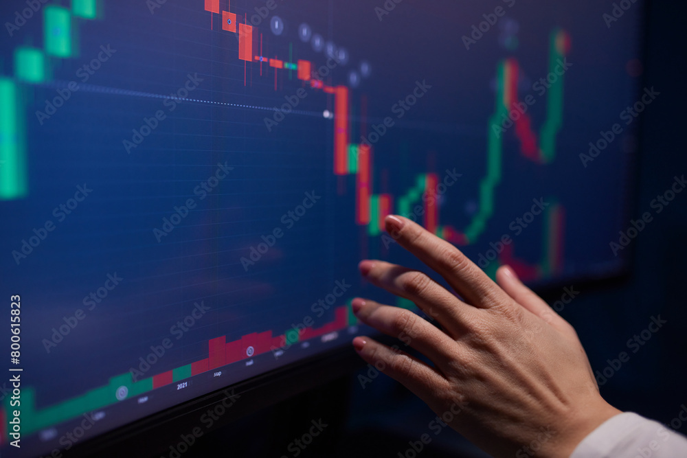 Finger to the graph on the monitor. Team of stockbrokers are having a conversation in a office with multiple display screens. Finger to the graph on the monitor. Team of stockbrokers are having a conversation in a office with multiple display screens.
