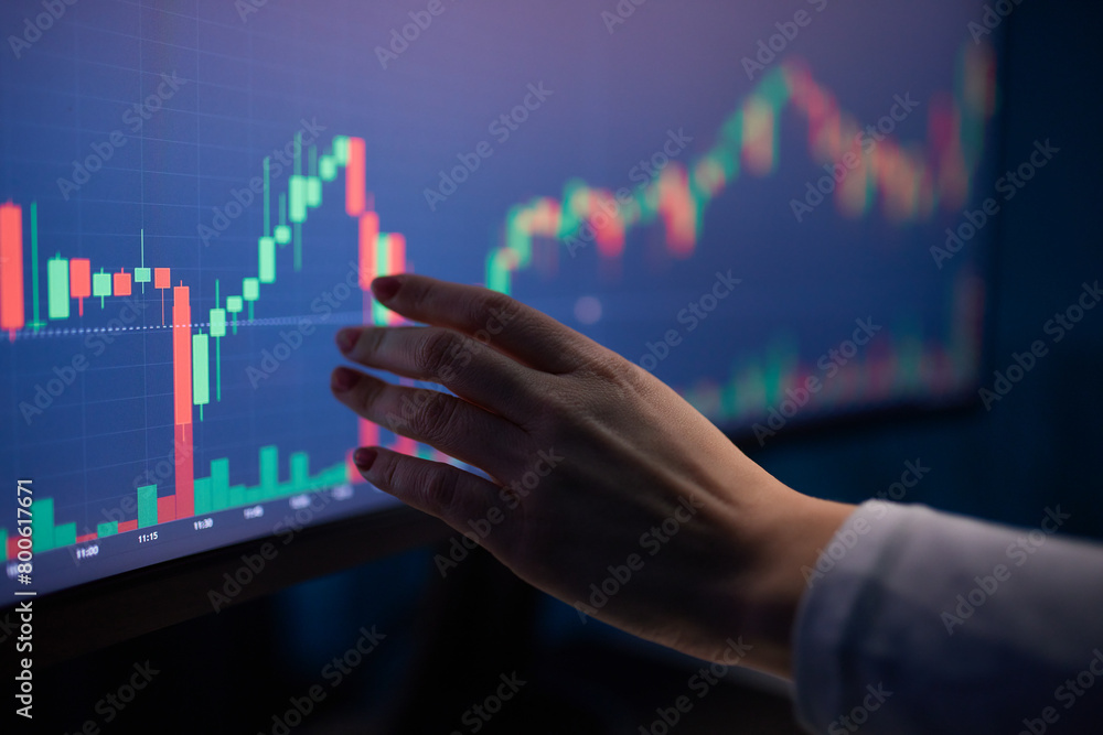 Finger to the graph on the monitor. Team of stockbrokers are having a conversation in a office with multiple display screens. Finger to the graph on the monitor. Team of stockbrokers are having a conversation in a office with multiple display screens.