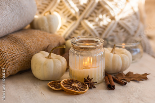 Autumn composition with aromatic candle, dry citrus, cinnamon, anise. Aromatherapy on a grey fall morning, atmosphere of cosiness and relax. Wooden background, pumpkin as decor