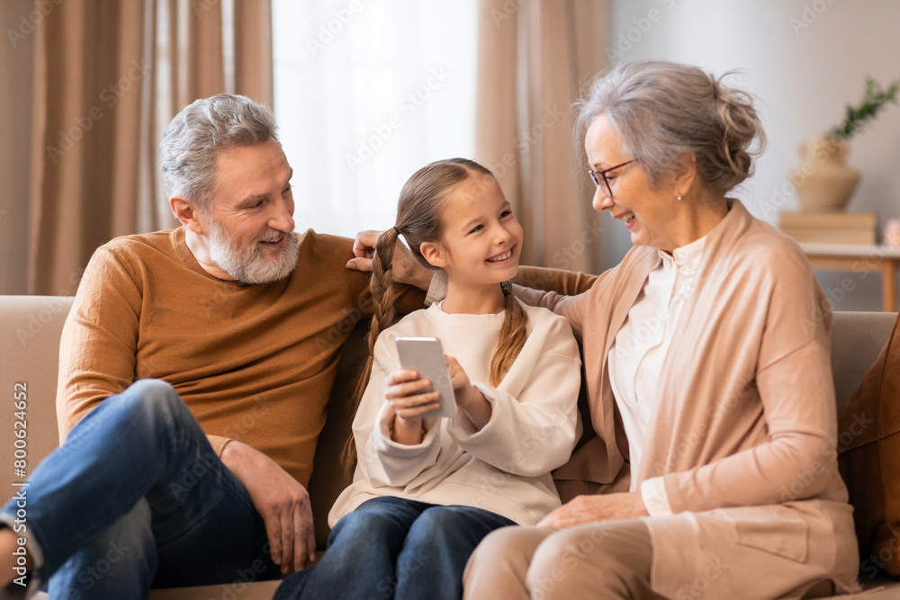 Family Sitting on Couch Looking at Cell Phone Family Sitting on Couch Looking at Cell Phone