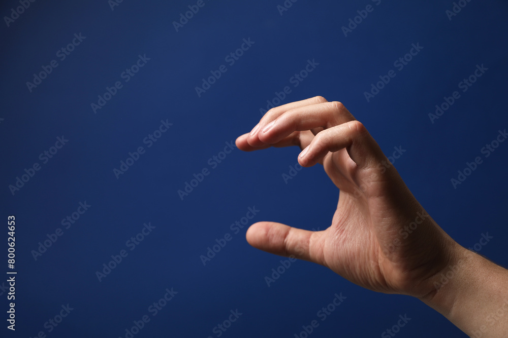 Man holding something in hand on blue background, closeup. Space for text Man holding something in hand on blue background, closeup. Space for text